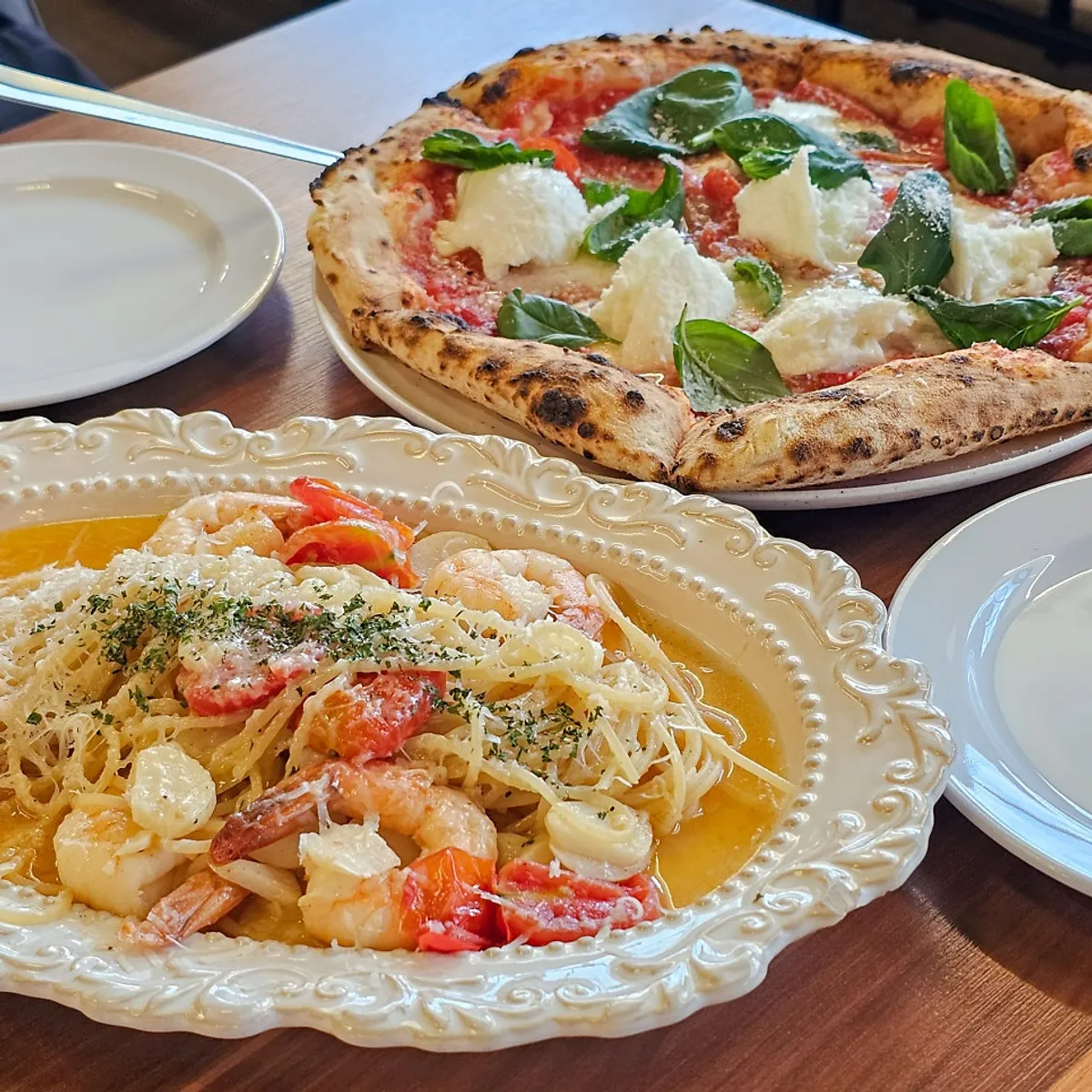 A table at Bonaricetta set with wood-fired pizza and pasta