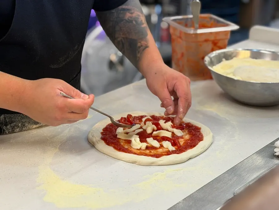 Adding tomato sauce and cheese toppings onto the dough