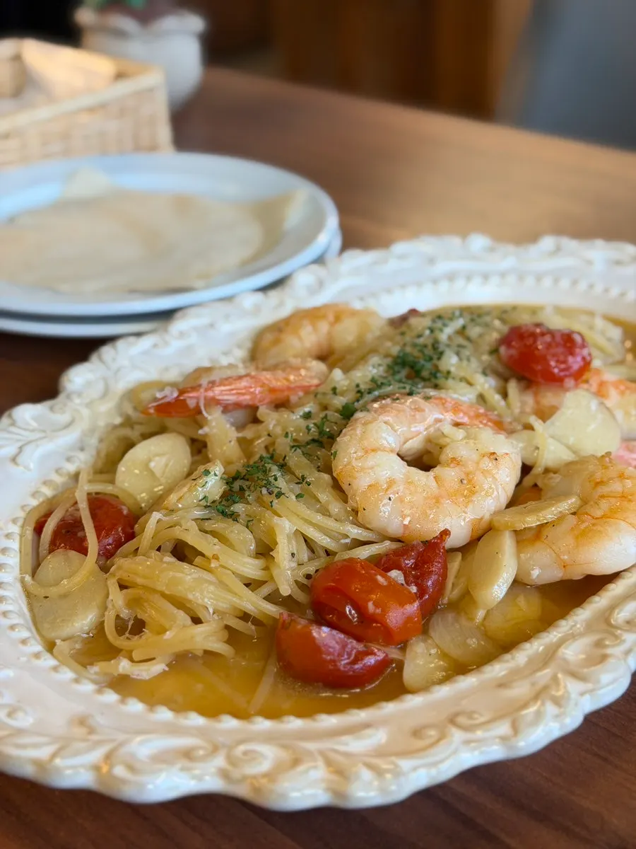 Vertical shot of oil pasta topped with chunky shrimp