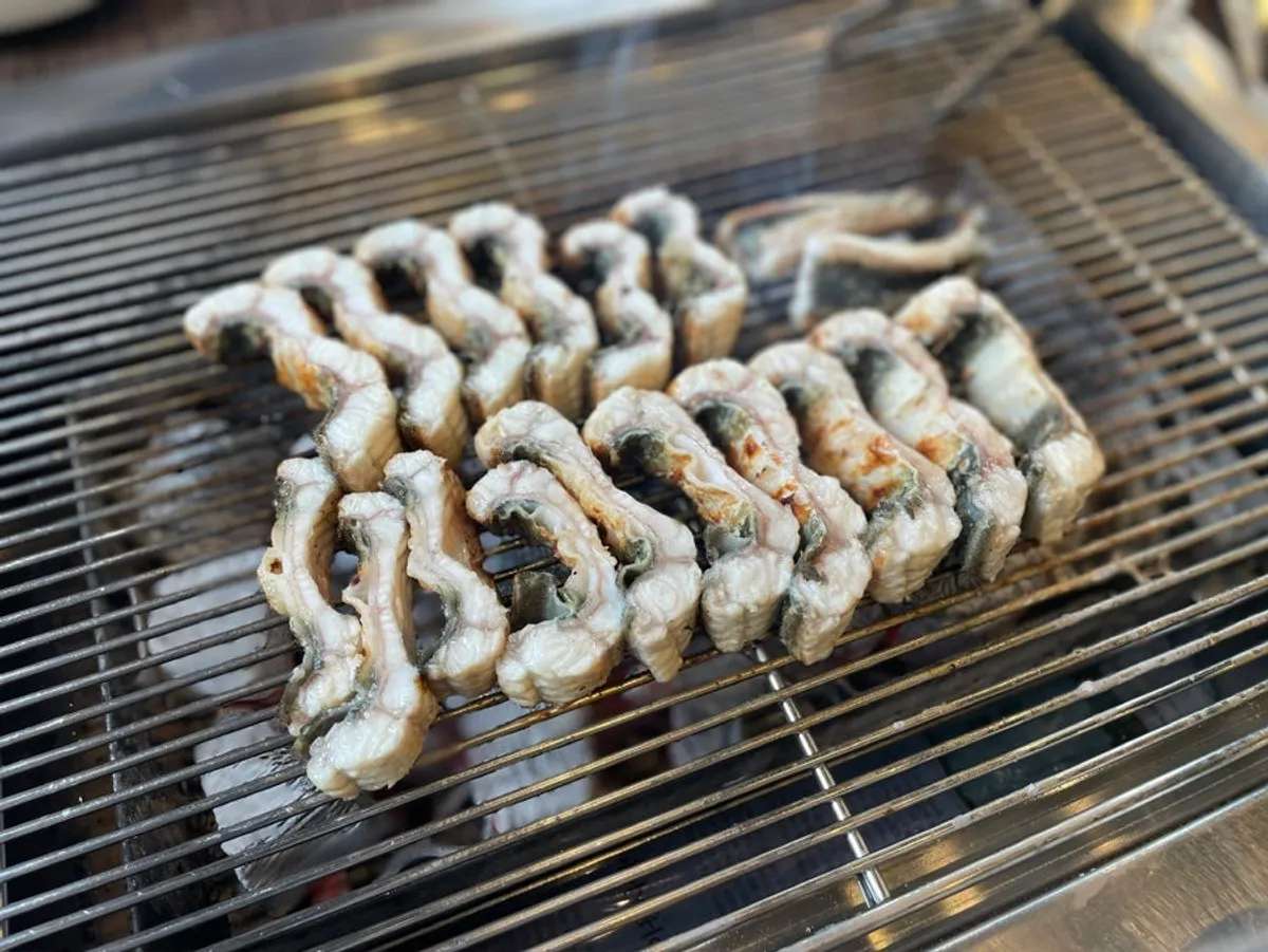 Salt-grilled eel cooking over the charcoal fire