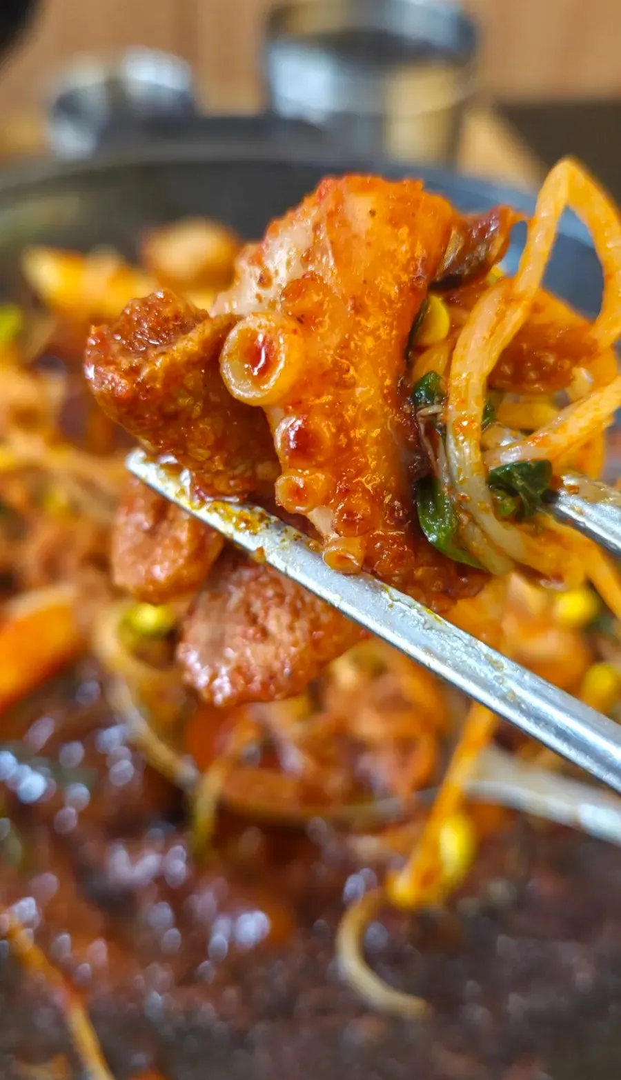 Chopsticks lifting duck meat and baby octopus together
