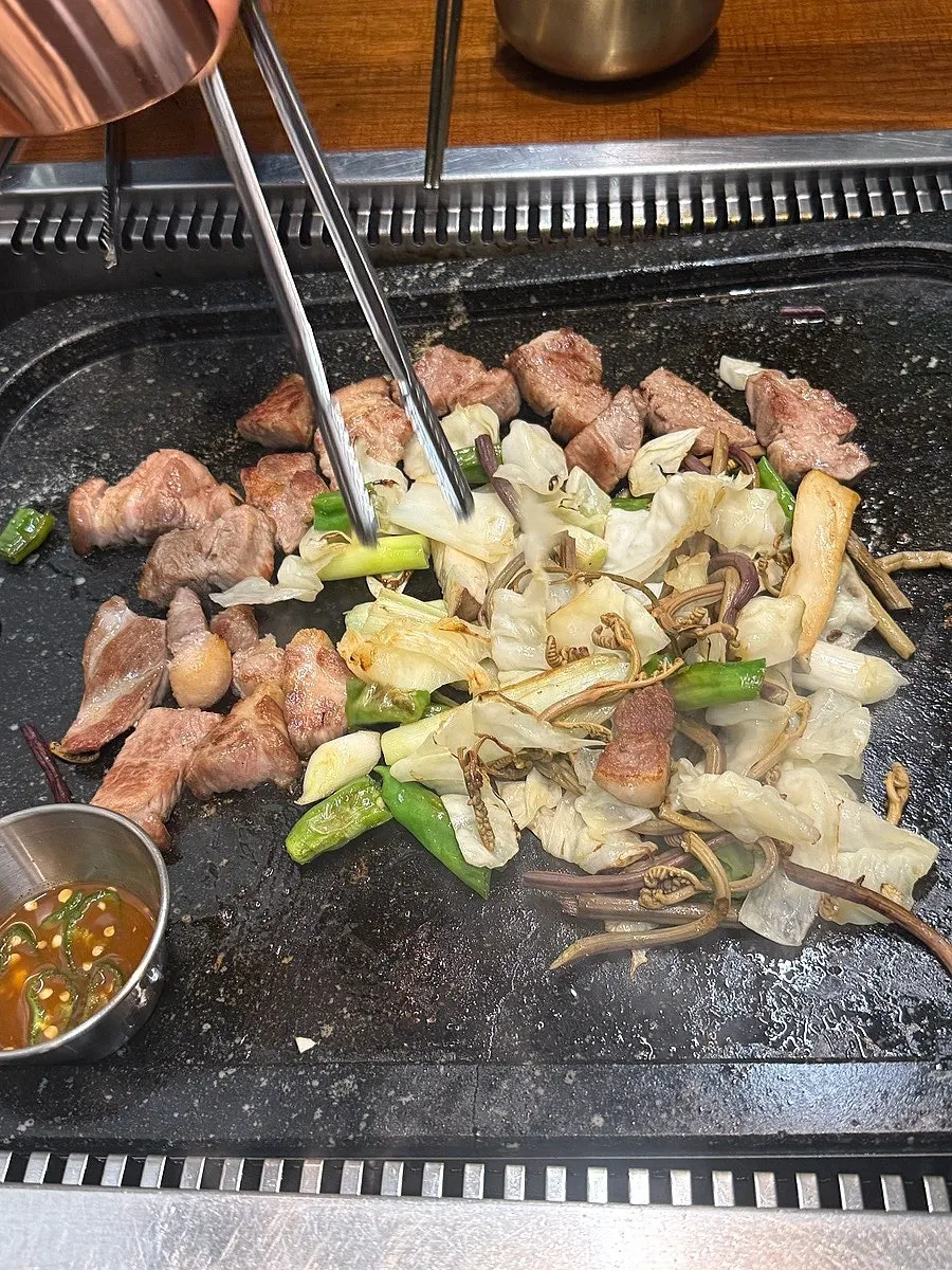 Pork neck cooking on the stone plate with vegetables