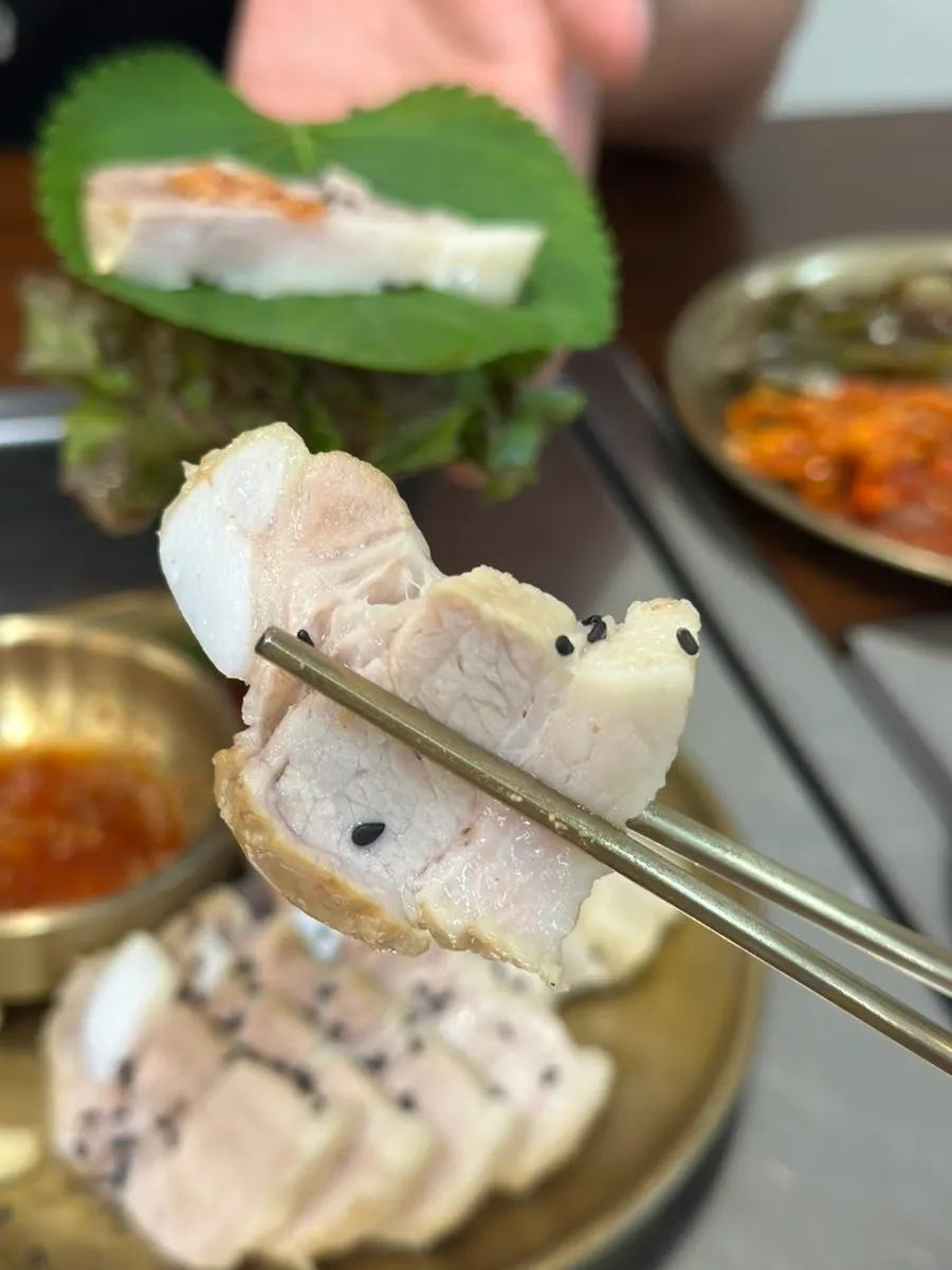 A piece of boiled pork wrapped in a perilla leaf