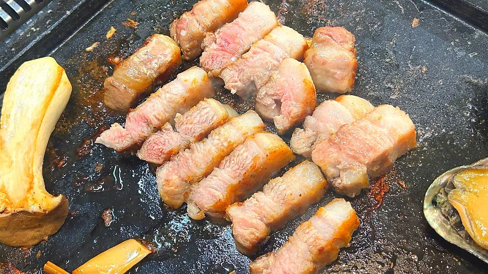 Pork belly and seafood cooking on the tabletop grill