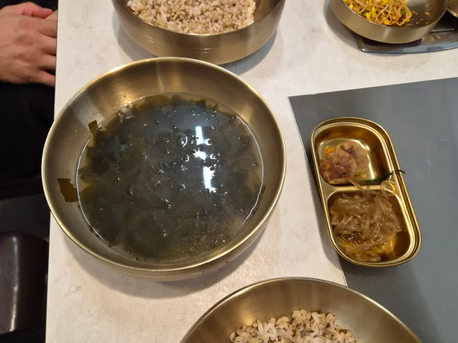 A kid's plate with seaweed soup, japchae and meatballs
