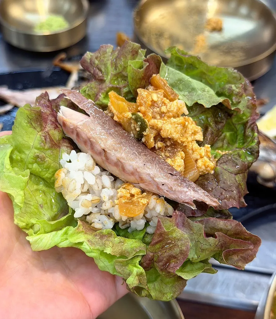 A piece of grilled mackerel topped with fresh wasabi