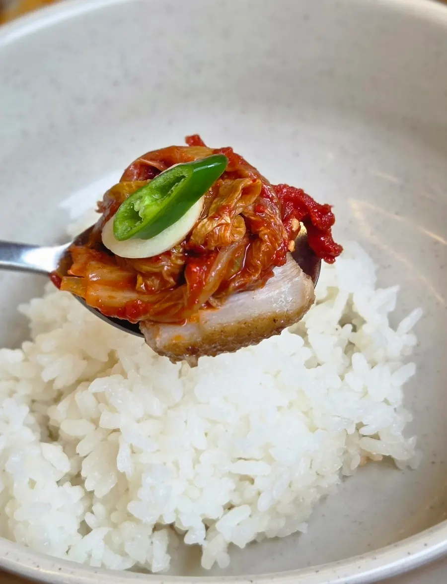A bossam wrap topped with kimchi and garlic