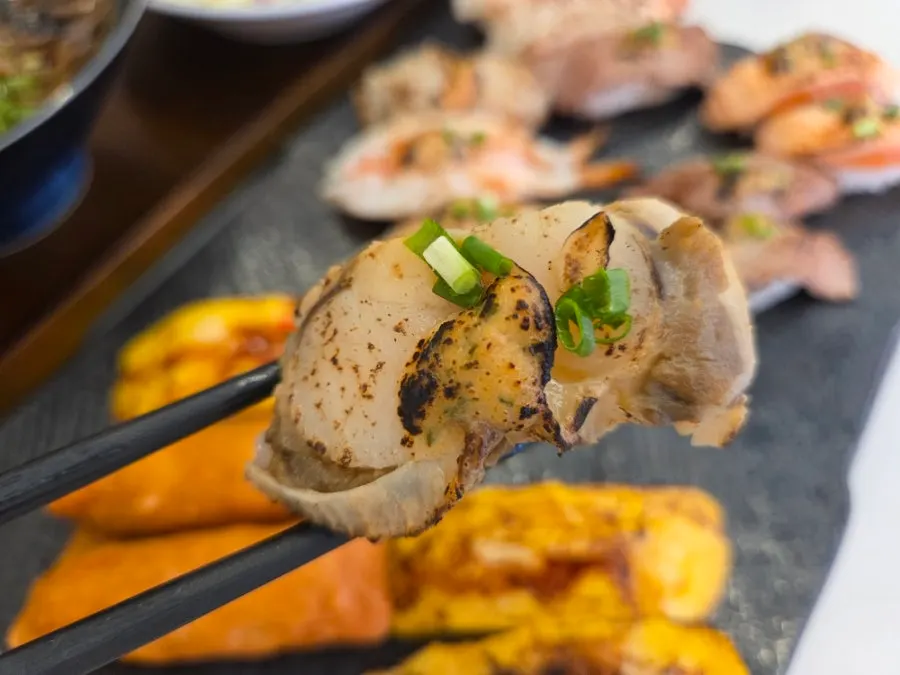 Flame-seared sushi held with chopsticks