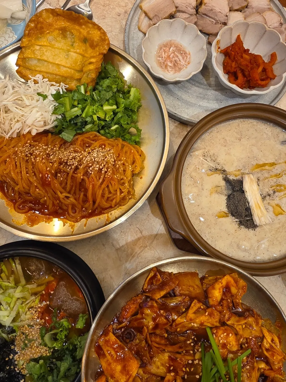Full spread of nakji deopbap set, bossam, mukbap, and bibim jjolmyeon