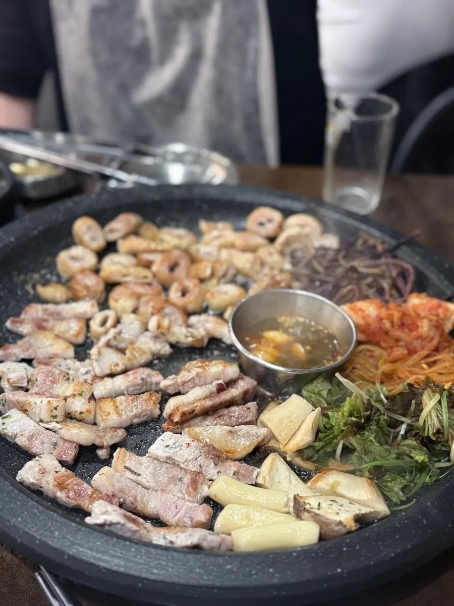 Raw pork belly grilling alongside gosari (bracken fern)