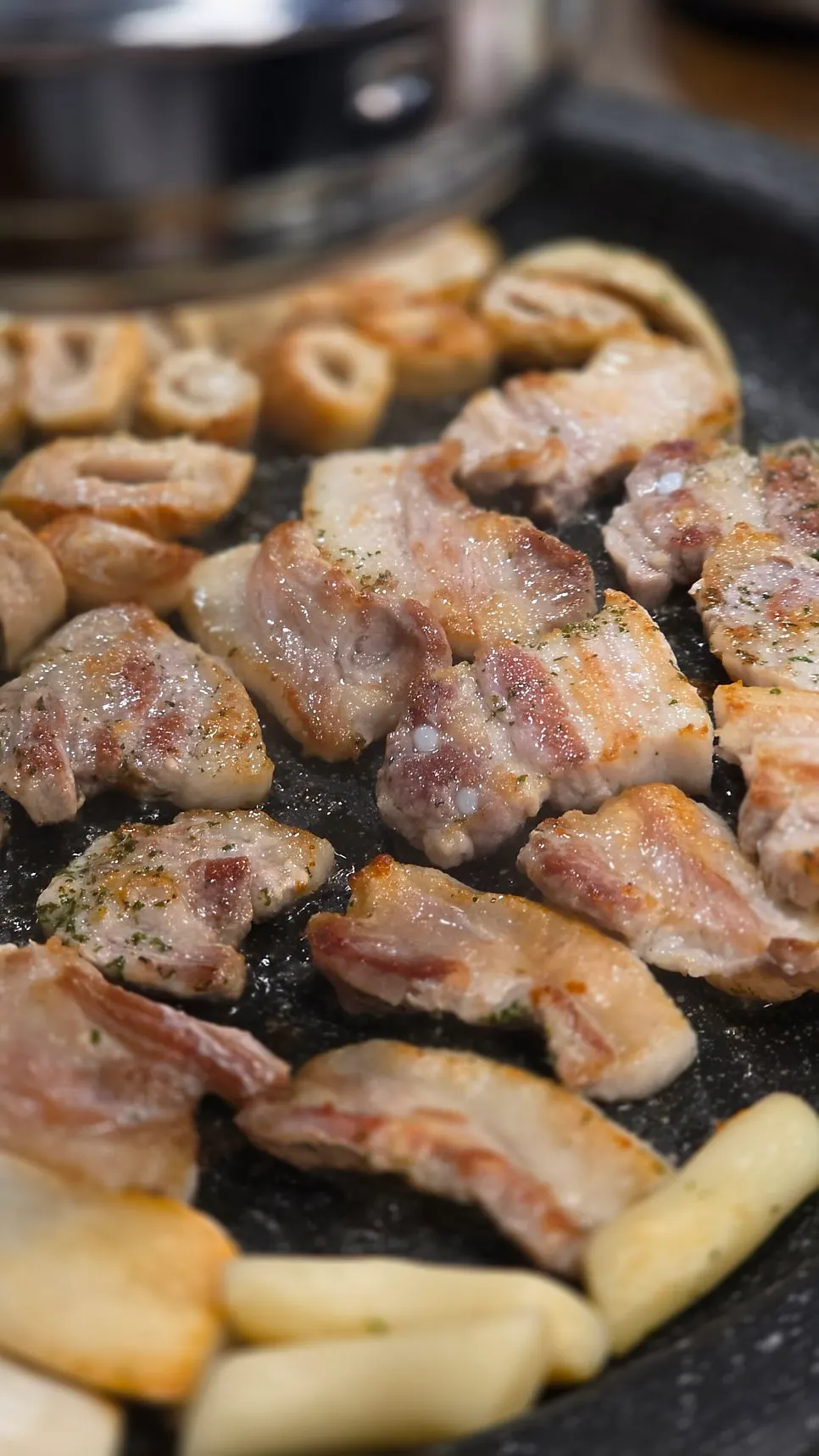 Raw pork belly cooking on the grill
