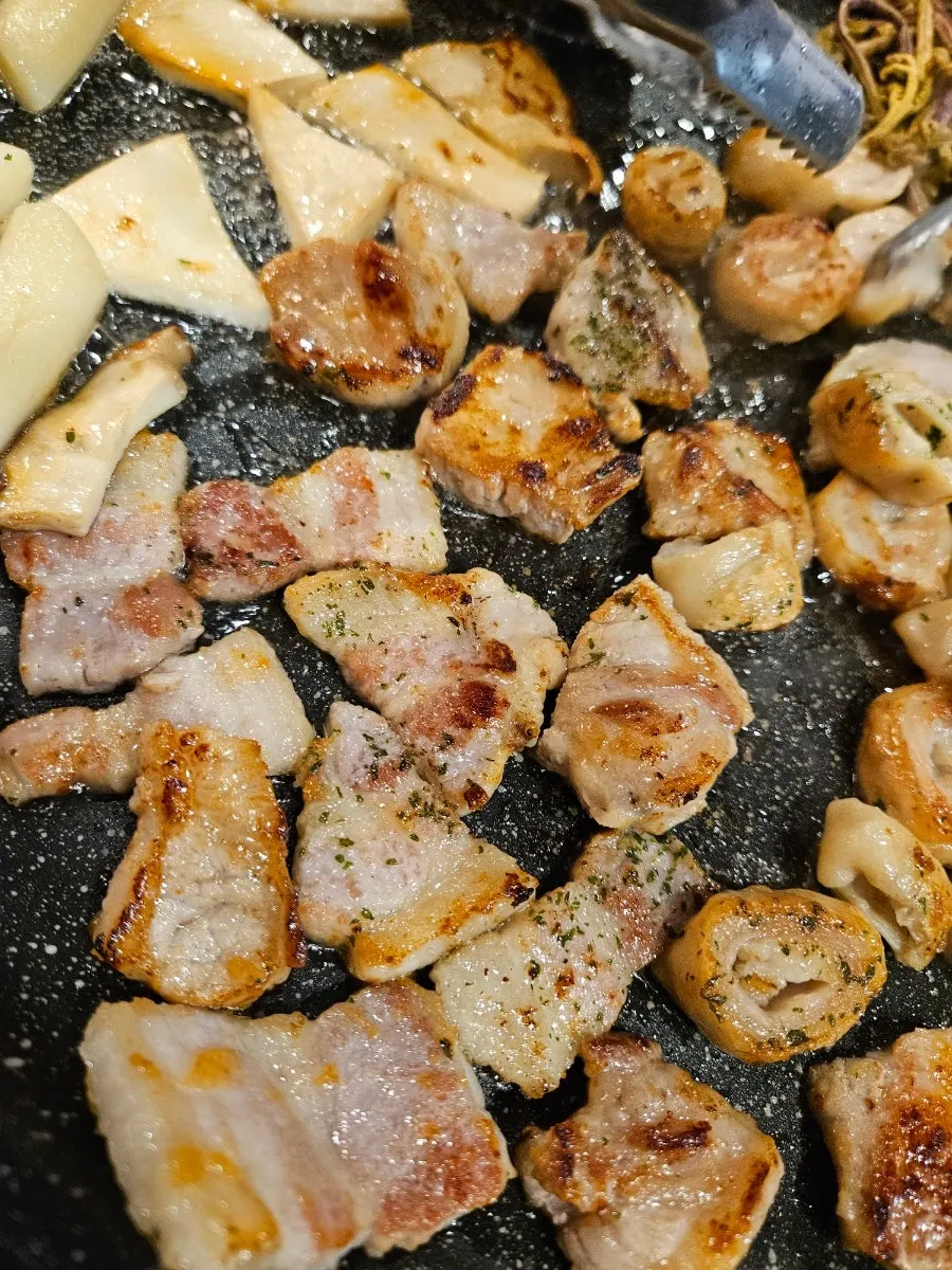 Samgyeopsal and makchang cooking on the stone grill plate