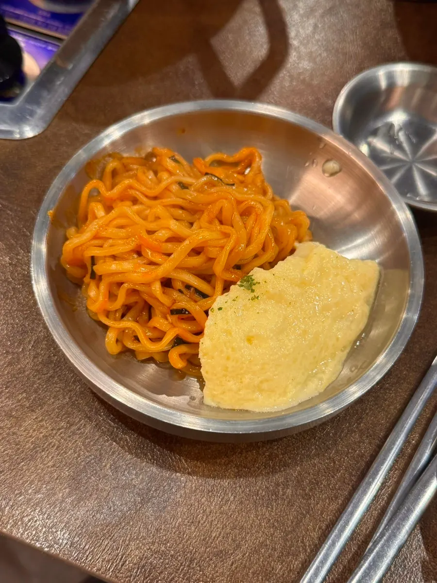 A bite of buldak-bokkeummyeon eaten together with the grilled meat