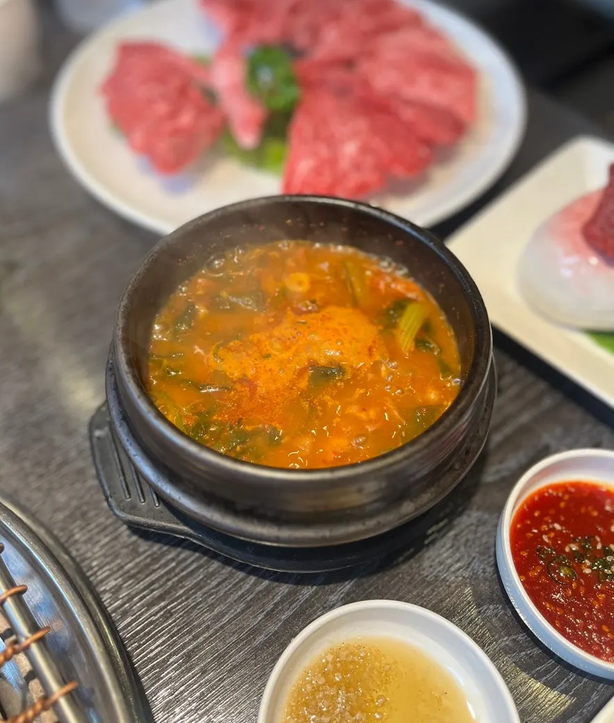 Hanwoo grilling over charcoal alongside side dishes