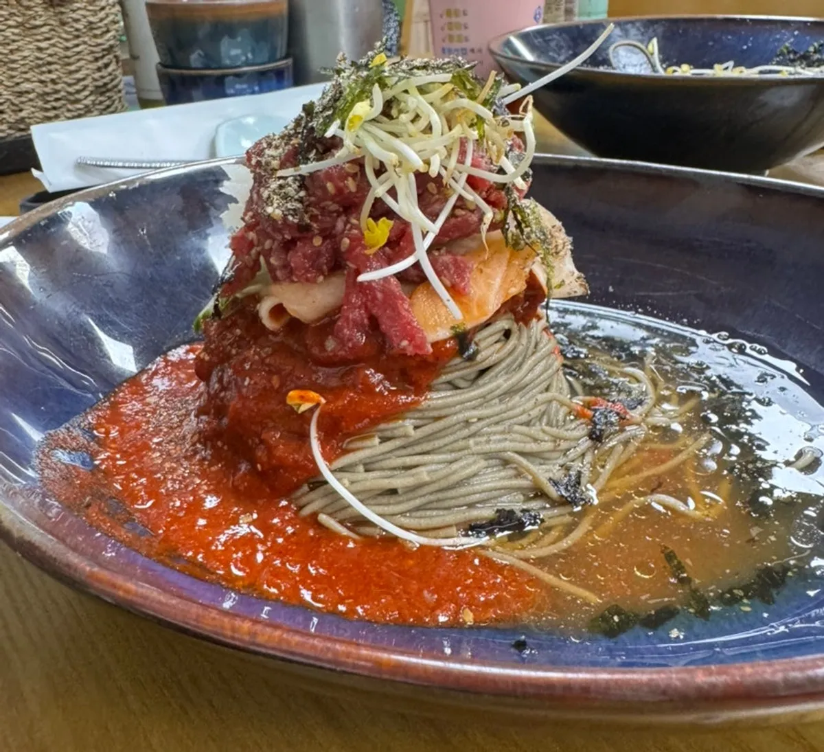 Idaepal buckwheat raw beef bibim noodles topped with beef and buckwheat sprouts