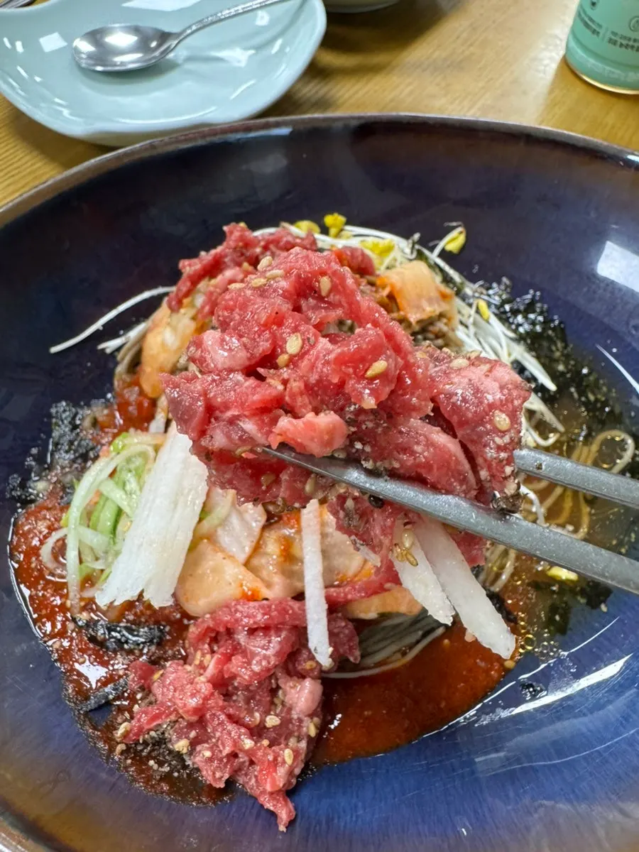 Raw beef bibim noodles cut with scissors