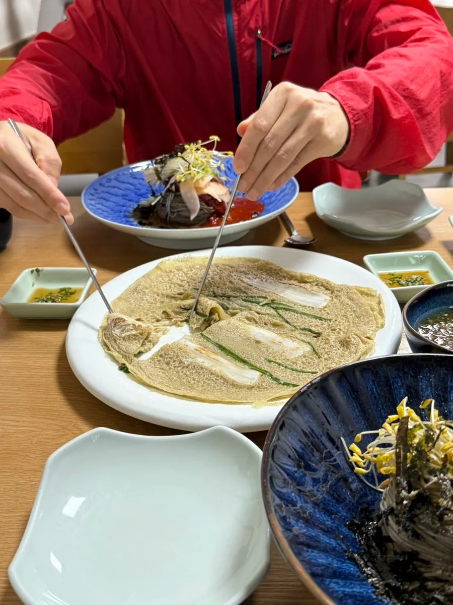 Wrapping bibim noodles in buckwheat pancake to eat