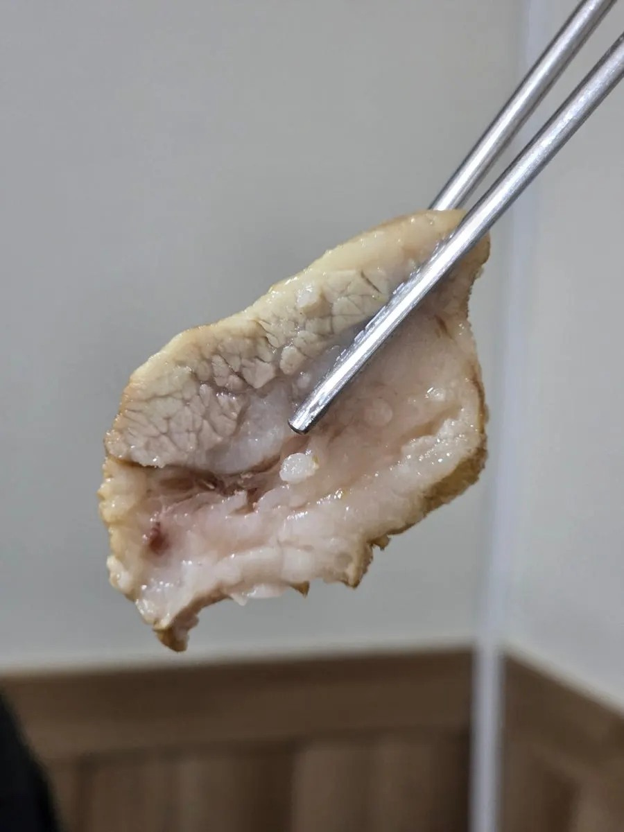 A piece of boiled pork topped with buckwheat sprouts and salted shrimp