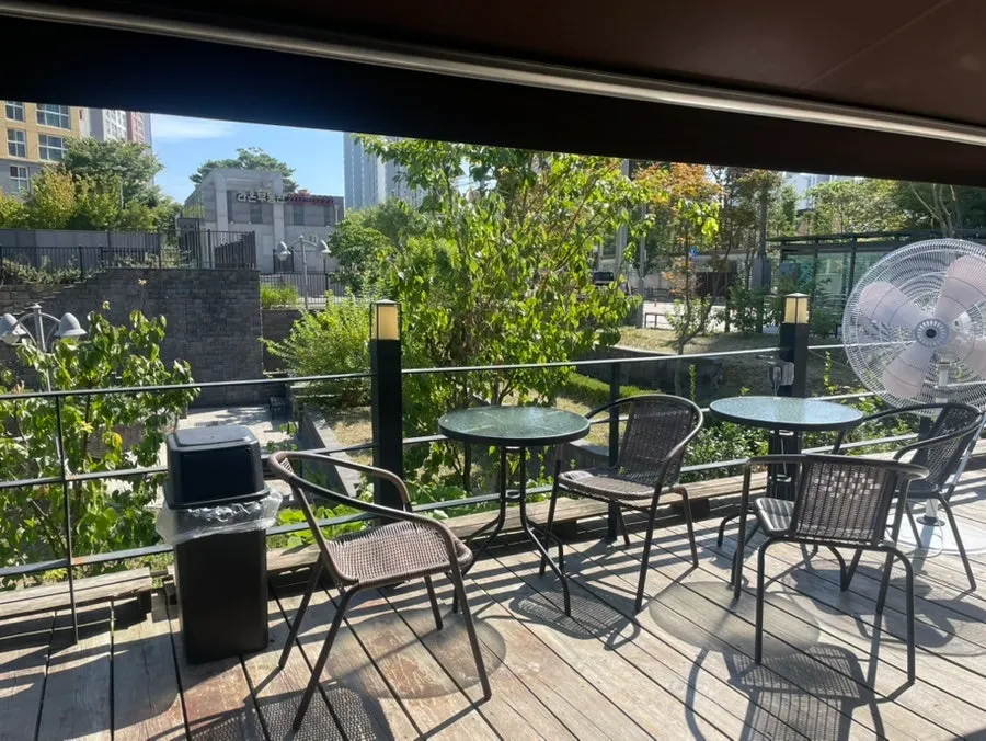 Outdoor tables at Boriook Main Branch set among green trees