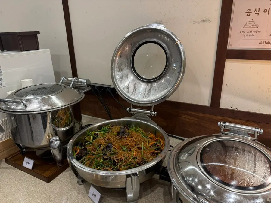 Side dish counter with fried items, braised tofu, and japchae