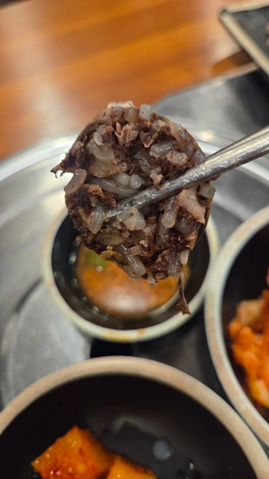 A spoonful of gukbap with rice mixed in and kimchi on top