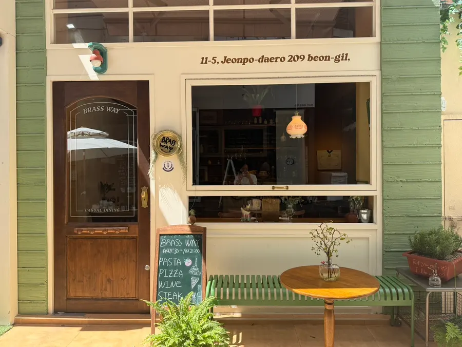 Storefront of Brassway with a mint-colored bench