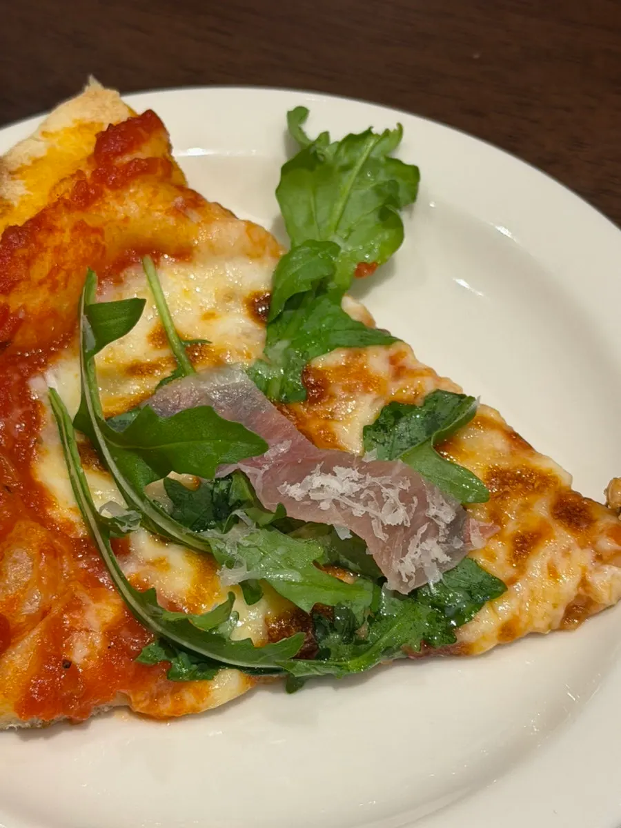 Close-up of prosciutto pizza piled high with arugula