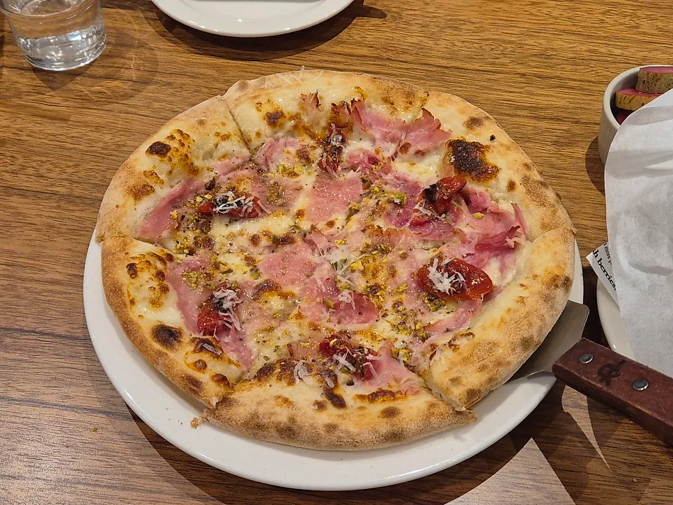 Jambon pizza topped with ham, nuts, and cheese