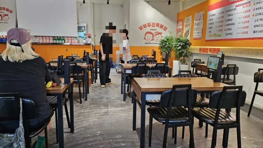 나무 테이블과 검정 의자가 놓인 매장 내부