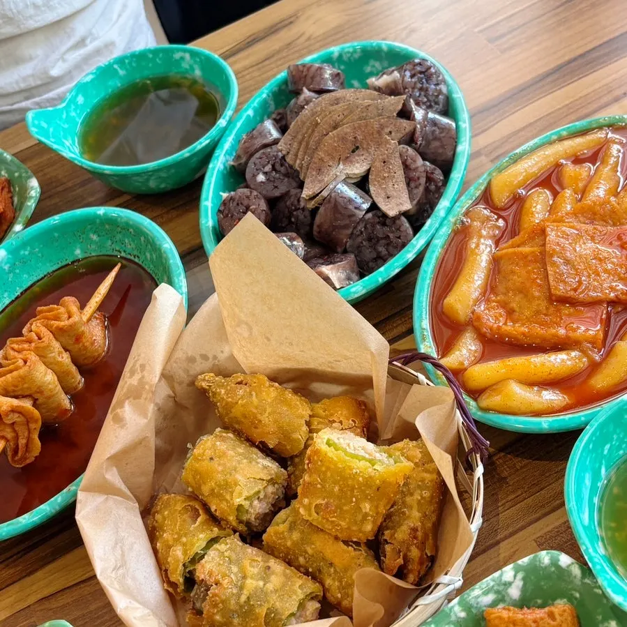 Full table spread of tteokbokki, sundae, spicy odeng, and fried chili