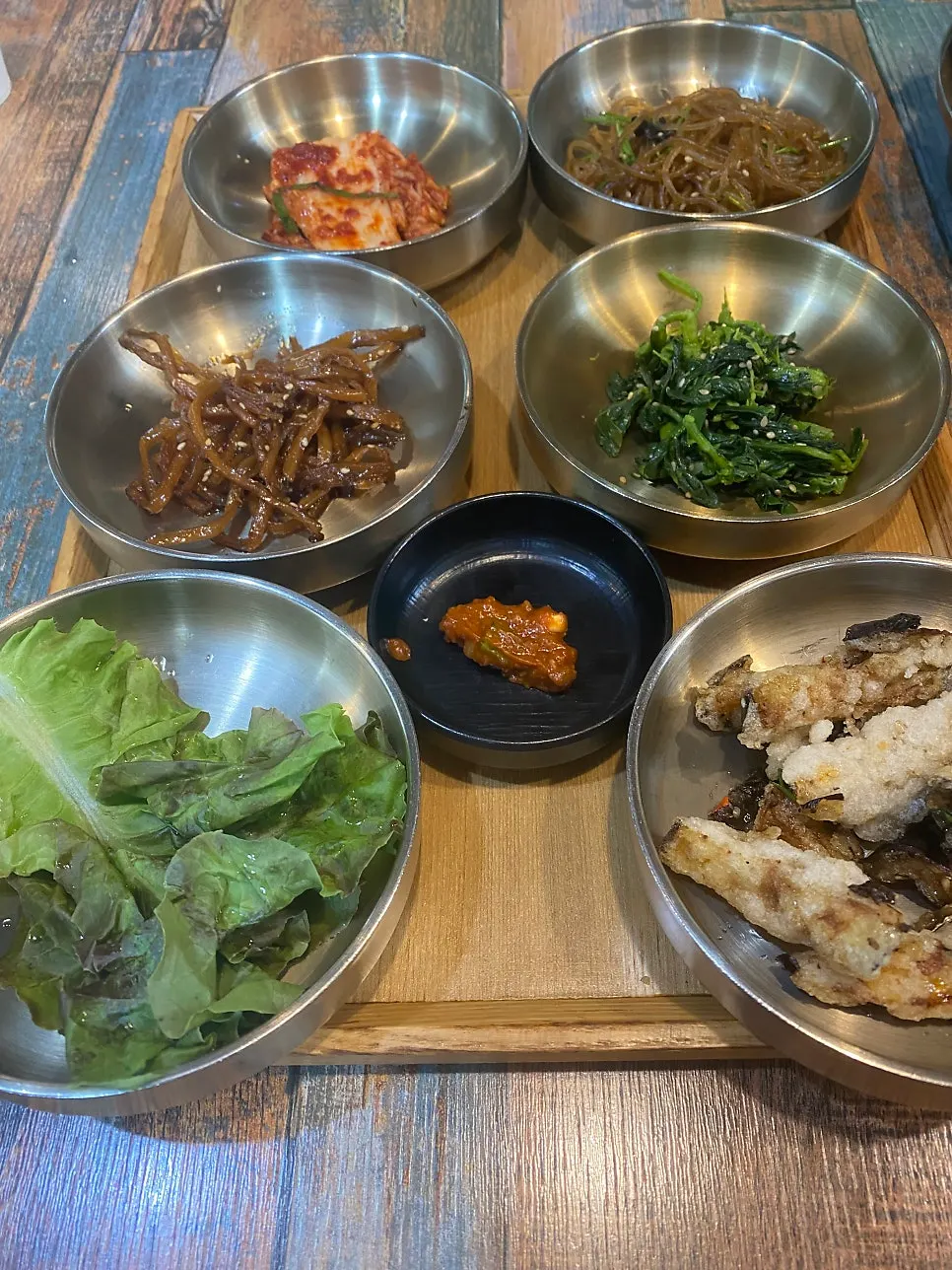 Table for two set with japchae, fried eggplant and other banchan