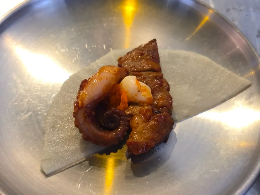 A bite of jjukkumi and pork belly mixed with bean sprouts