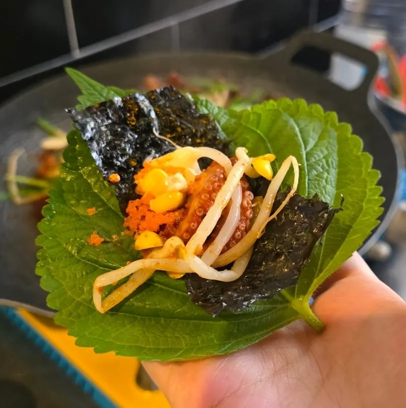 A bite of jjukkumi wrapped in seaweed