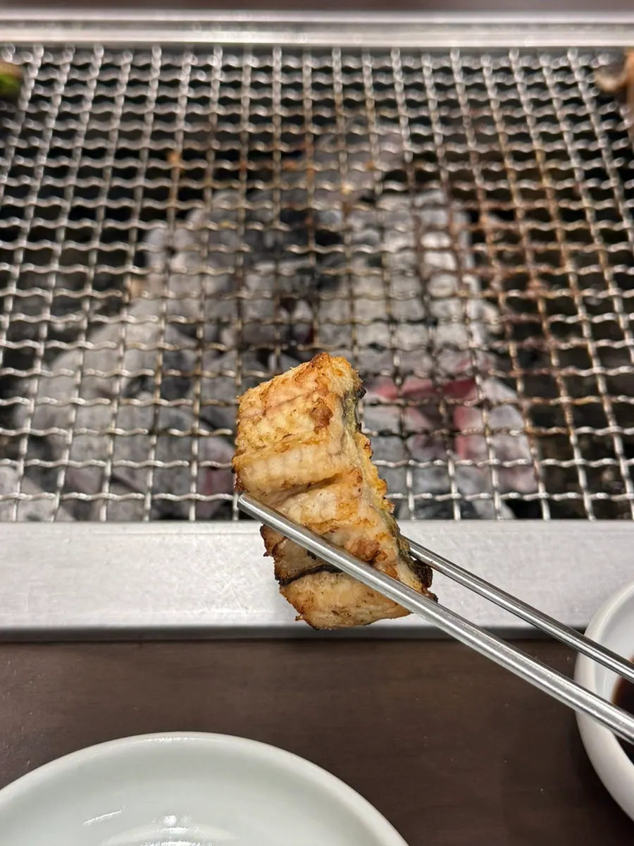 Grilled eel and shishito peppers placed away from the fire
