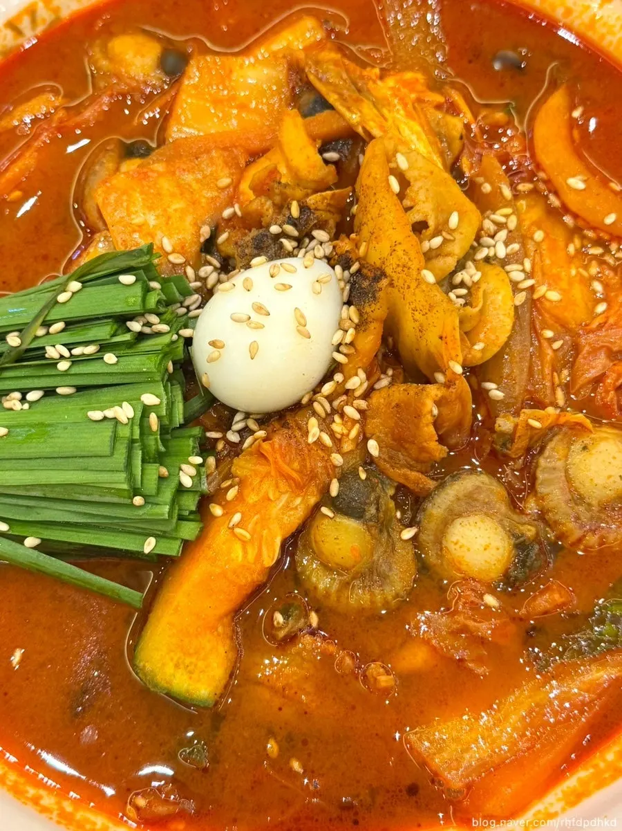 A bowl of spicy jjamppong loaded with seafood and vegetables