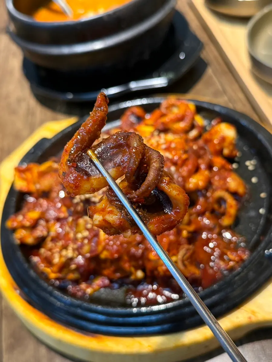 A bite of octopus stir-fry lifted with chopsticks