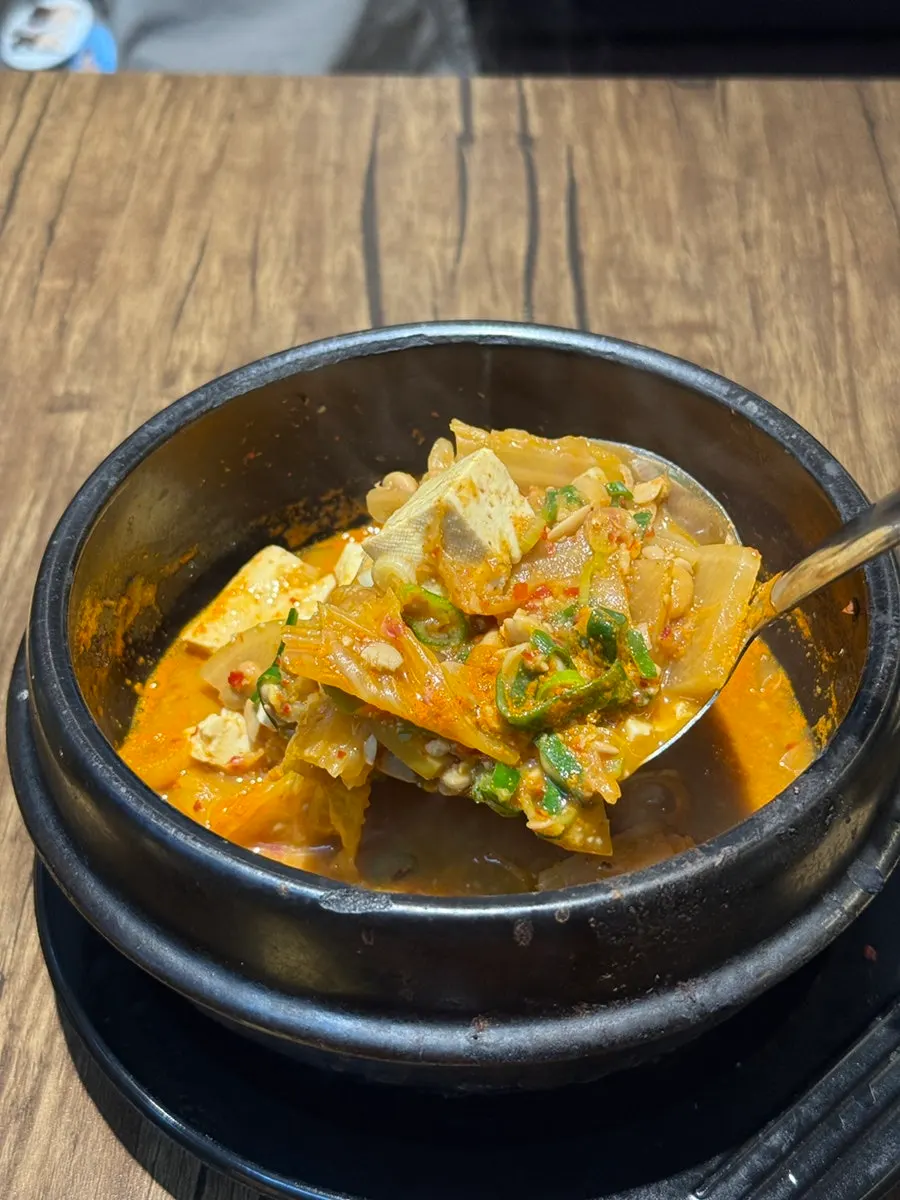 A ladle of cheonggukjang stew with tofu and cabbage
