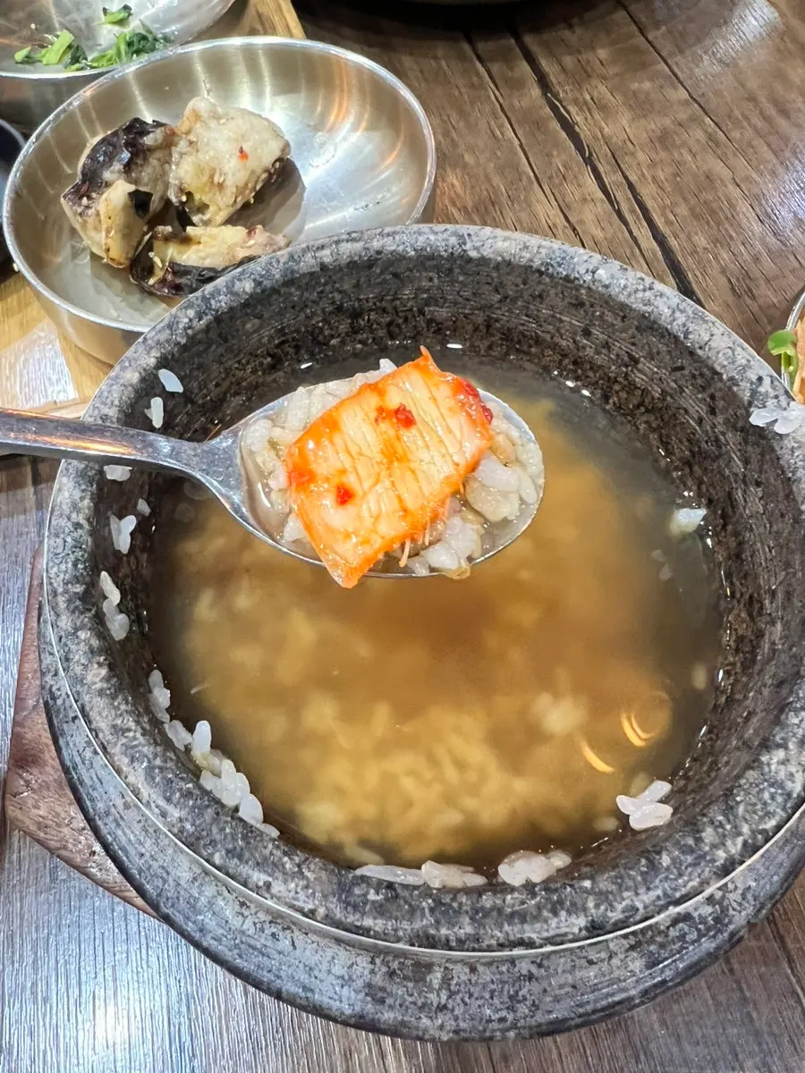 A spoonful of sungnyung next to leftover banchan