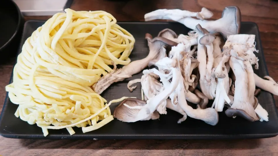 육수에 칼국수 사리와 버섯을 넣은 냄비