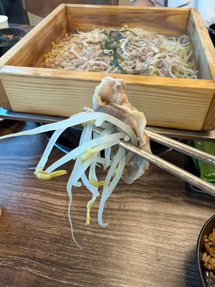 A bite of steamed duck eaten with bean sprouts