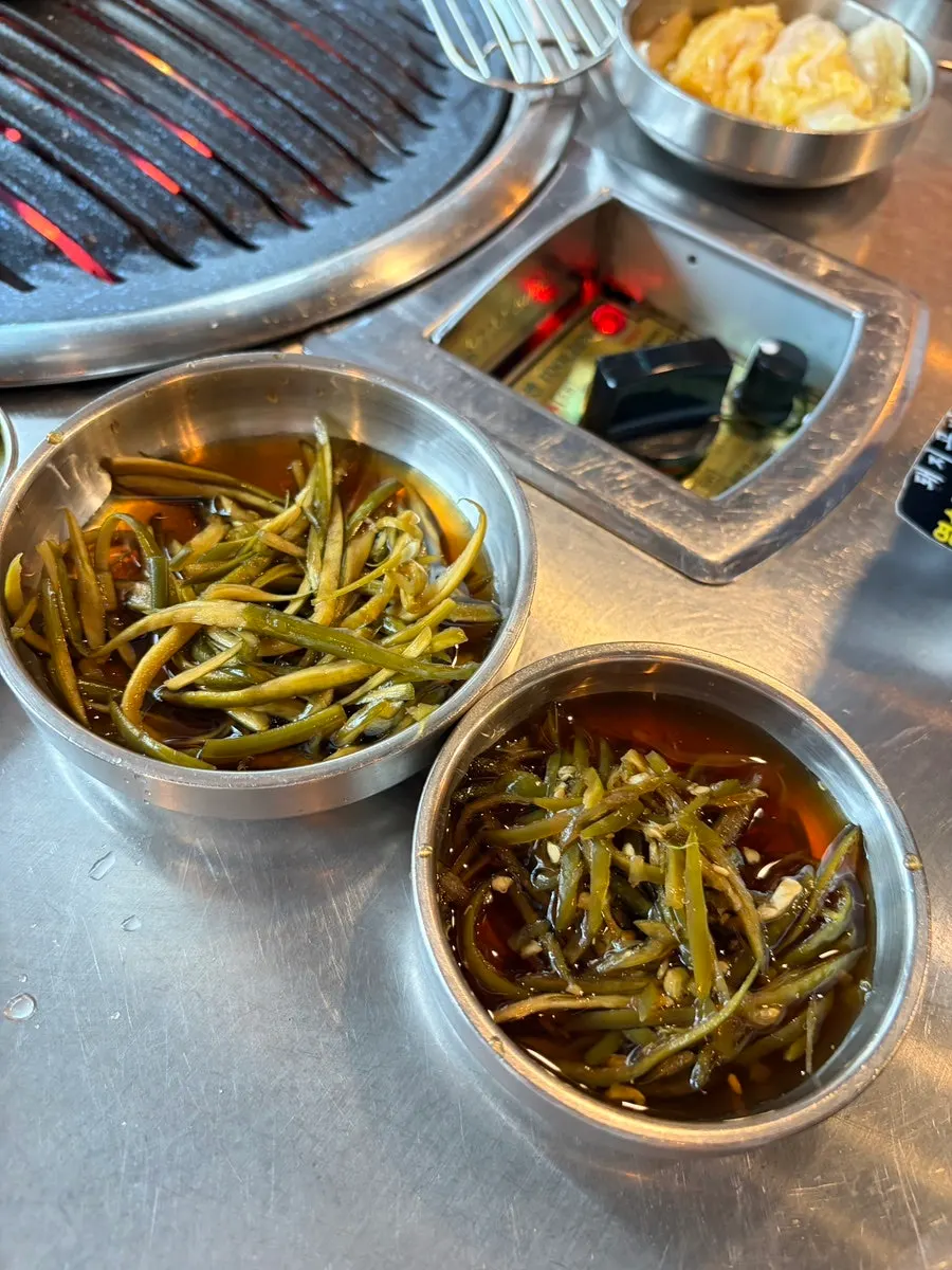 Side dishes of pickled peppers and pickled garlic scapes