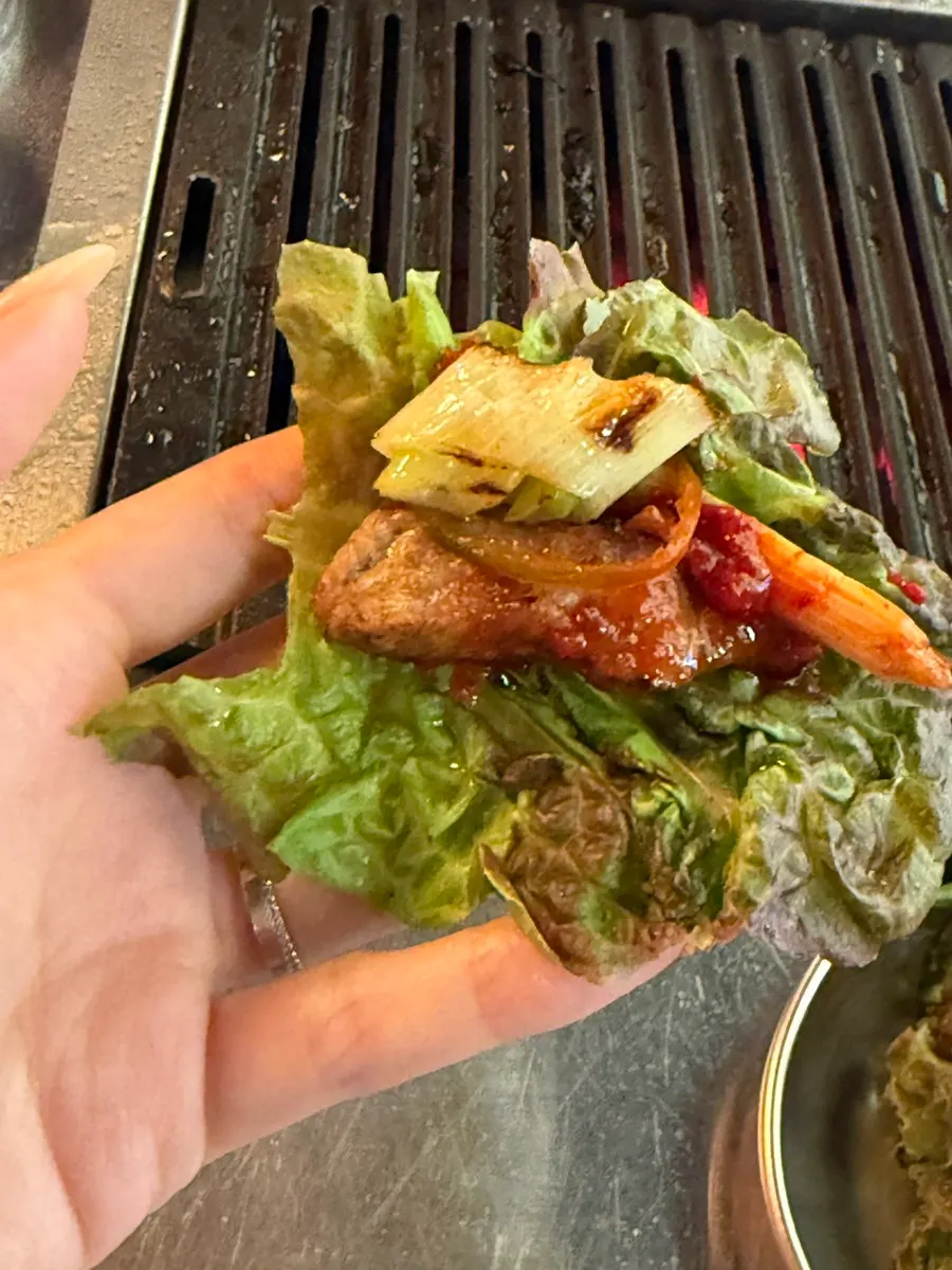 Meat paired with pickled radish wraps and green onion kimchi