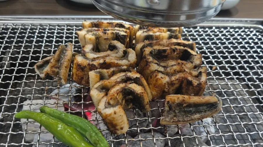 Staff member grilling eel over charcoal