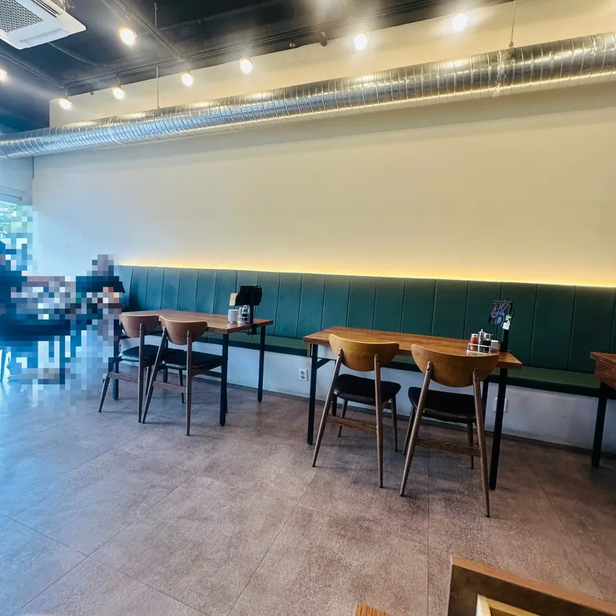 Interior with wood-toned tables and deep green sofa seating