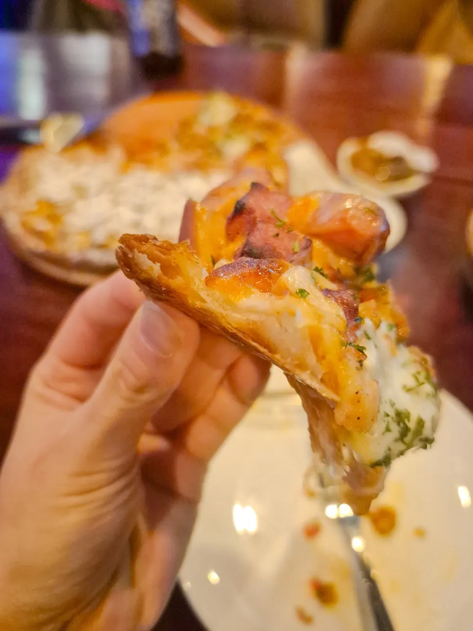 A slice of the half-and-half ham cheese pizza with heavy toppings