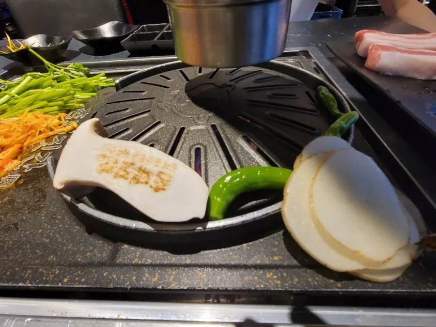 Grill with pork belly and side ingredients cooking together