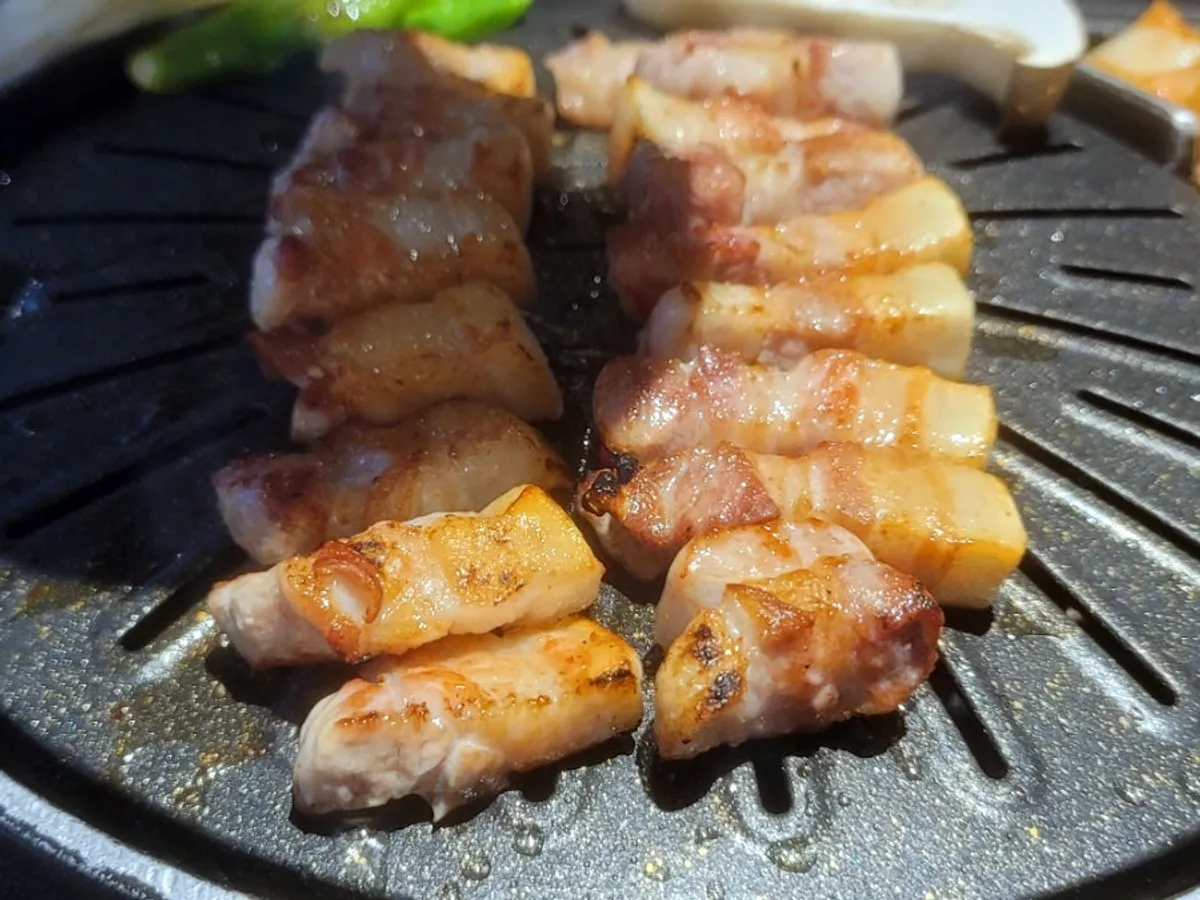 Staff member grilling pork belly at Cham Dwaejitgan
