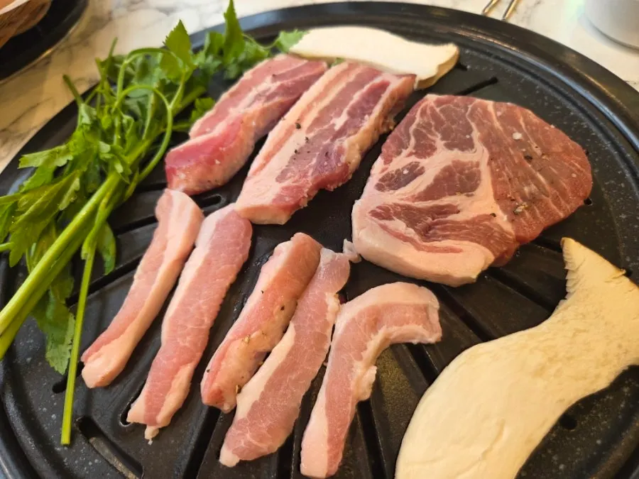 A platter of raw pork neck, pork belly, pork jowl, and smoked makchang