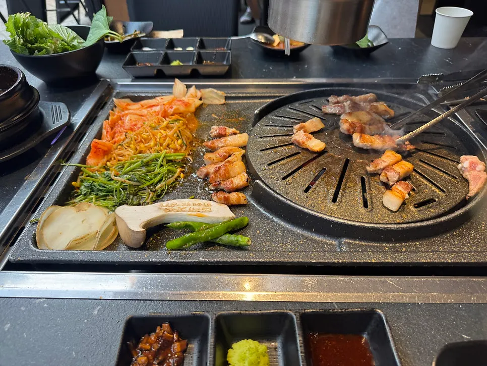Staff member grilling pork belly on the tabletop grill