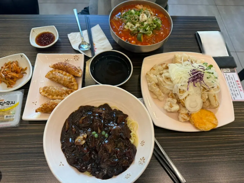 Table spread with soft tofu jjamppong noodles, jijon jjajang, and tangsuyuk
